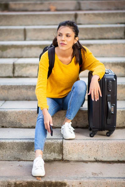 若い女性の完全な長さの肖像画で階段に座ってスーツケース荷物袋 — ストック写真