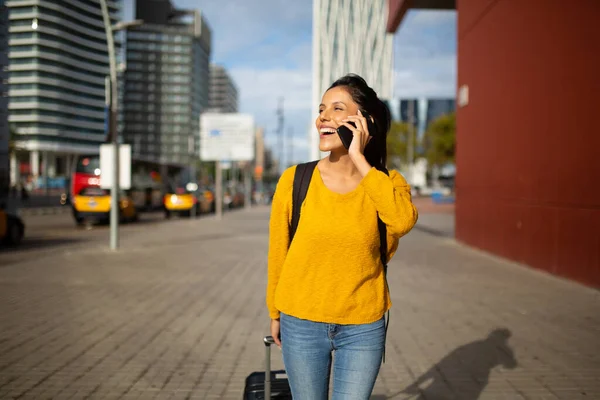 Portret Uśmiechniętej Młodej Kobiety Spacerującej Walizką Rozmawiającej Przez Telefon — Zdjęcie stockowe