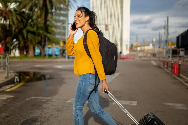 带着手提箱和手机散步的快乐旅行妇女的侧面肖像 — 图库照片