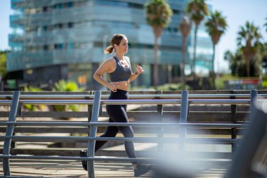 Köprüde koşan sporcu kadının tam boy portresi 