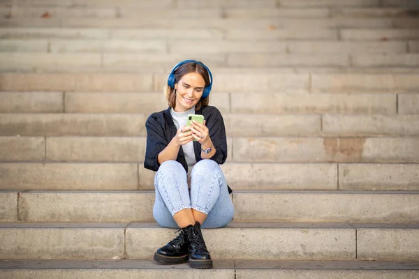 Potret Wanita Tersenyum Yang Duduk Tangga Mendengarkan Musik Dengan Ponsel — Stok Foto