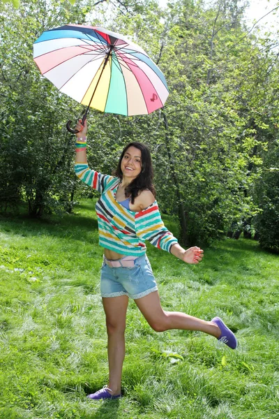 Beautiful young girl posing on nature with color umbrella — Stock Photo, Image