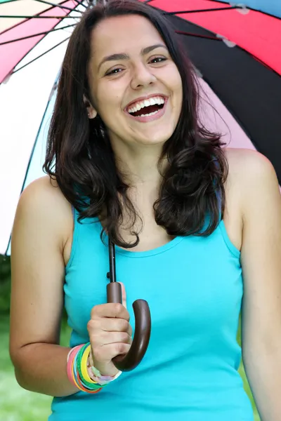 Schönes junges Mädchen posiert in der Natur mit farbigem Regenschirm — Stockfoto