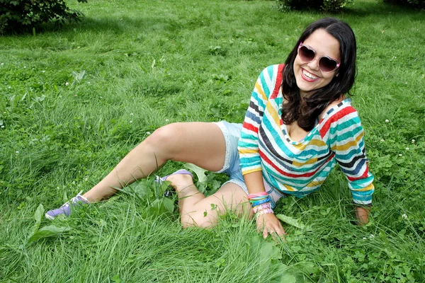 Piękna, młoda dziewczyna okulary, siedząc na trawie — Zdjęcie stockowe