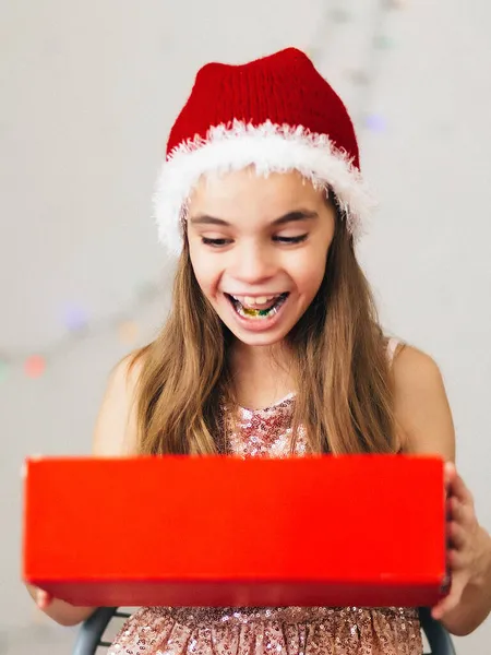 Elinde kırmızı bir hediye kutusu tutan bir kız. - Sürpriz. Noel 'i kutlamak