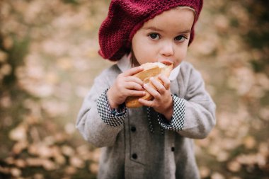 2 yaşındaki güzel bir kız hamur işi yer, doğada bir rulo