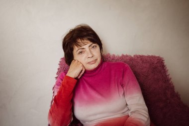 50 yaşında güzel bir kadın, bir ev sandalyesinde oturuyor. Genç bir büyükannenin portresi. seçici odak.