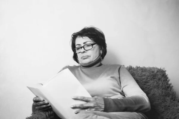 Beautiful woman 50 years old, reading a book. Black-white portrait of a young grandmother. selective focus.