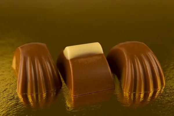 Chocolates on a golden background — Stock Photo, Image