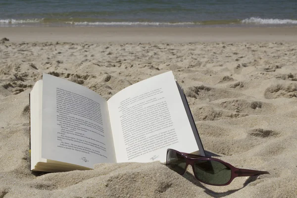 Book and sunglasses on the sand — Stock Photo, Image