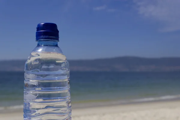 Botella de agua a la orilla del mar — Foto de Stock