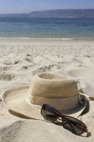 Straw hat and sunglasses on the beach — Stock Photo, Image