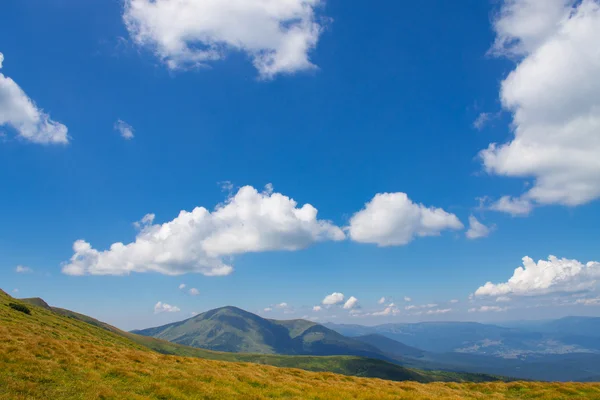 Montanhas e azul céu nublado fundo — Fotografia de Stock