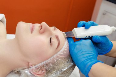 Genç bir kadının derisini temizlemek için ultrasonik çürüme prosedürü. Kozmetoloji Ofisi.