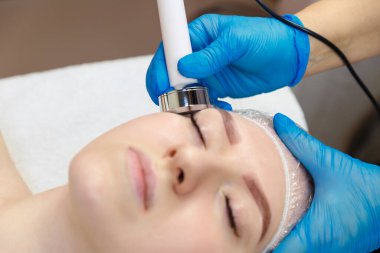 Genç bir kadın spa salonunda yüz boşluğu yaptırıyor. Güzellik salonundaki yüz hatlarının gelişimi..