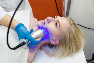 Yüzünün düzeltilmesi ve cilt bakımı için soğuk terapi uygulanan genç bir kadın..