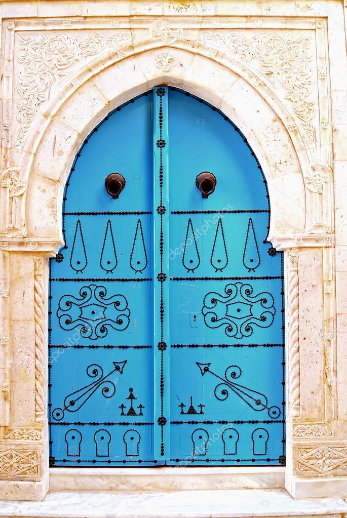 A-blue-door-with-black-studs-and-stone-ornament-at-doorway-in-Tu