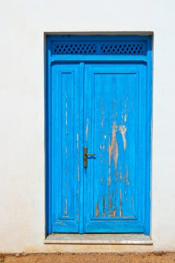 Blue-Door-on-a-White-Wall-doorway-with-Wooden-grate-Above