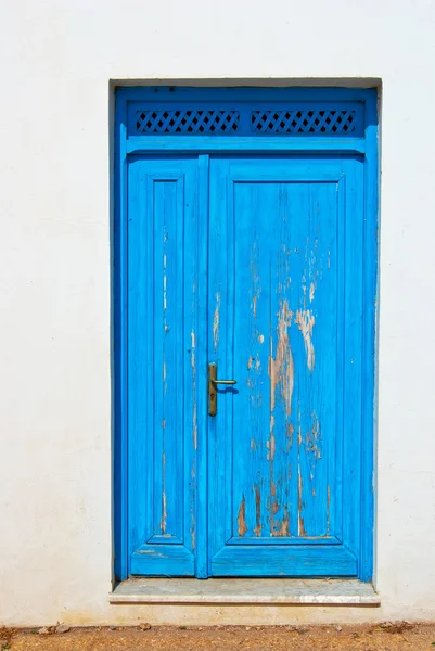 Blue-door-on-a-white-wall-doorway-with-wooden-grate-above — Stock Photo, Image