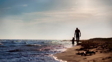 Baba ve oğul gün batımında denize