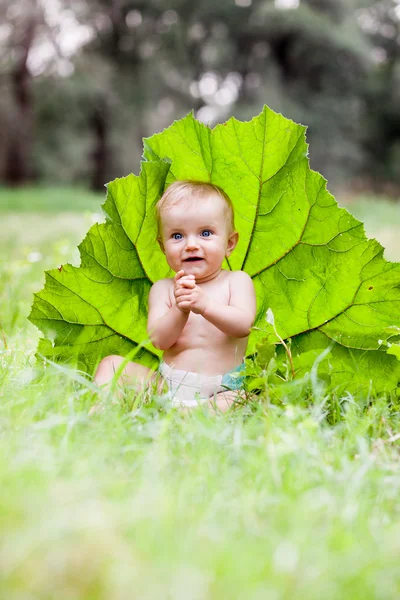 春の芝生の上に緑の芝生に囲まれて座って美しい男の子 — ストック写真