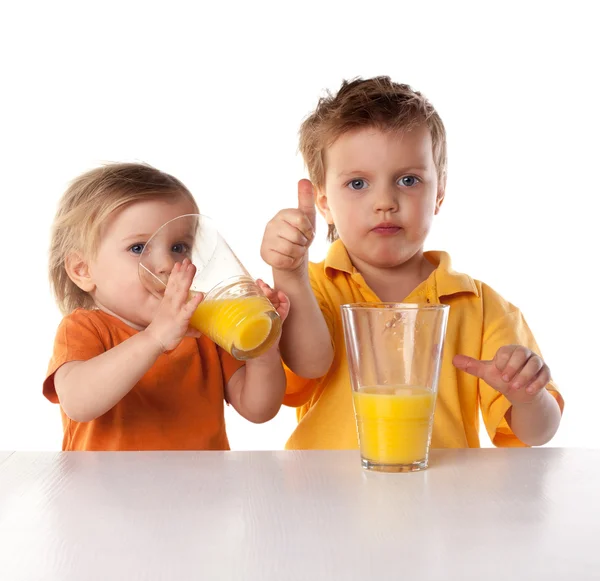 Happy children drink orange juice isolated on white — Stock Photo, Image
