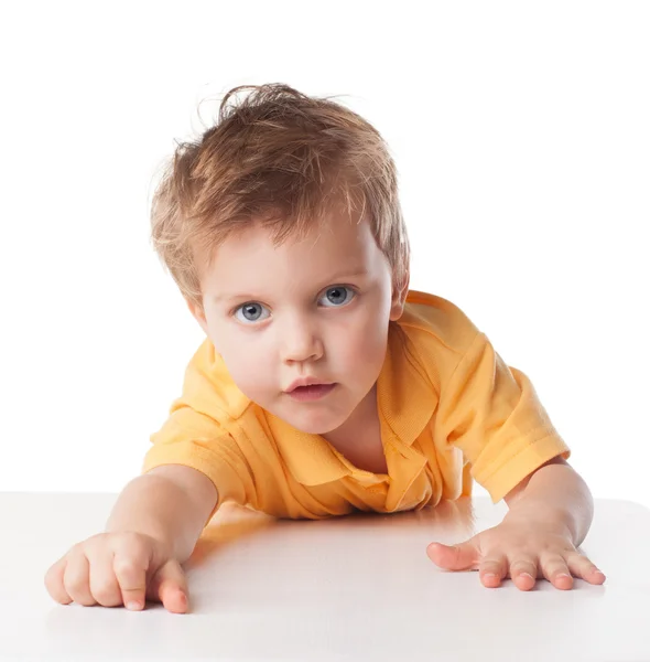 Ritratto di un simpatico bambino allegro, che sorride seduto a tavola, isolato sul bianco — Foto Stock