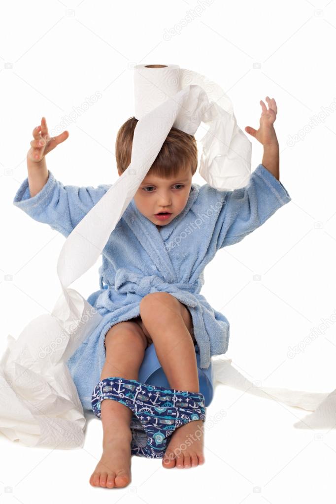 Little boy sitting on potty, rolls of toilet paper beside