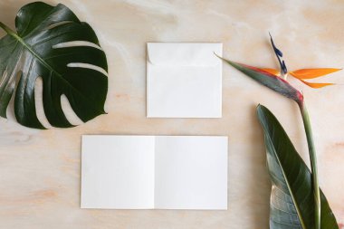 Yazın düzenlenmiş düğün masaüstü kırtasiyesi modeli. Boş bir tebrik ve davetiye kartı. Boş alanlı yeşil tropikal yapraklar.