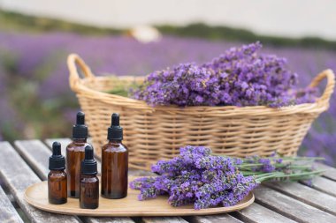 Şişede lavanta yağı ve gri ahşap masadaki damlalar. Yatay yakın plan.