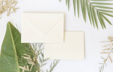 Yazın düzenlenmiş düğün masaüstü kırtasiyesi modeli. Boş bir tebrik ve davetiye kartı. Boş alanlı yeşil tropikal yapraklar.