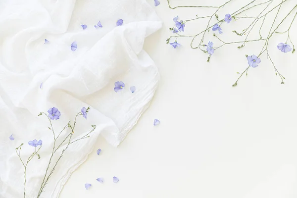 Açık renkli tekstil üzerinde beyaz arkaplanda çiçek açan keten çiçekleri. — Stok fotoğraf