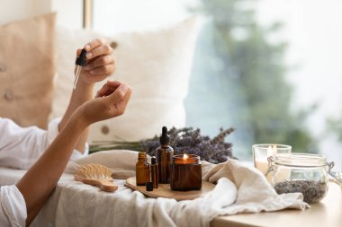 Esaslı lavanta yağları cam bir şişede. Kız cildine ve saçlarına önem veriyor. İskandinav iç mimarisi.