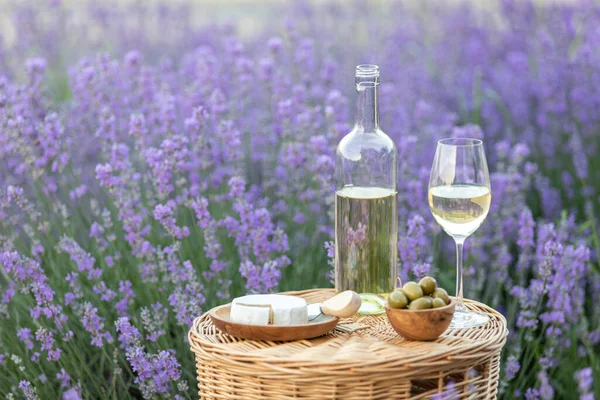 Lavanta tarlasında bir bardak beyaz şarap. Arka planda mor çiçekler. — Stok fotoğraf