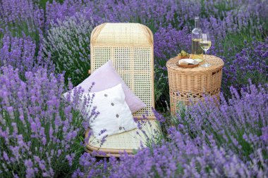 Lavanta tarlasında bir bardak beyaz şarap. Arka planda mor çiçekler