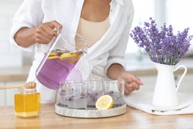 Genç bir kız limon ve lavantadan limonata yapıyor. Yaz içkisi hazırlayan kadın