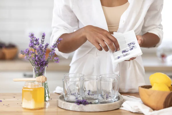 Genç bir kız limon ve lavantadan limonata yapıyor. Yaz içkisi hazırlayan kadın