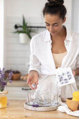 Genç bir kız limon ve lavantadan limonata yapıyor. Yaz içkisi hazırlayan kadın