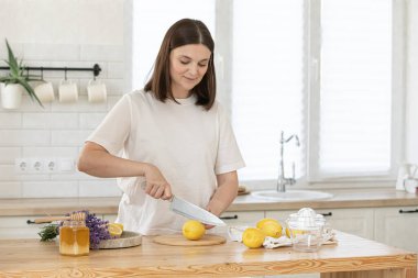 Tahta tahtada limon kesen genç bir kadın. Taze şarap hazırlığı. Lavanta ve limon