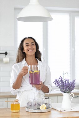 Genç bir kız limon ve lavantadan limonata yapıyor. Yaz içkisi hazırlayan kadın