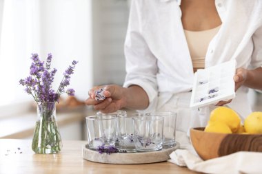 Genç bir kız limon ve lavantadan limonata yapıyor. Yaz içkisi hazırlayan kadın
