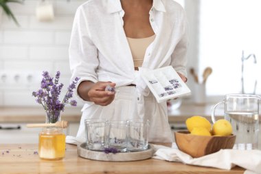 Genç bir kız limon ve lavantadan limonata yapıyor. Yaz içkisi hazırlayan kadın