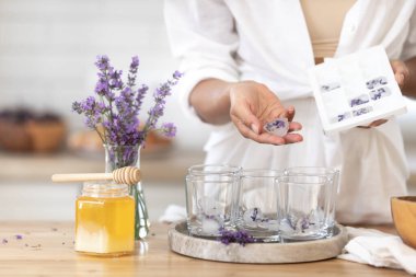 Genç bir kız limon ve lavantadan limonata yapıyor. Yaz içkisi hazırlayan kadın
