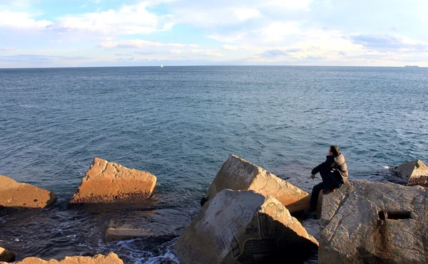 Homme assis sur la grande pierre vers la mer . — Photo