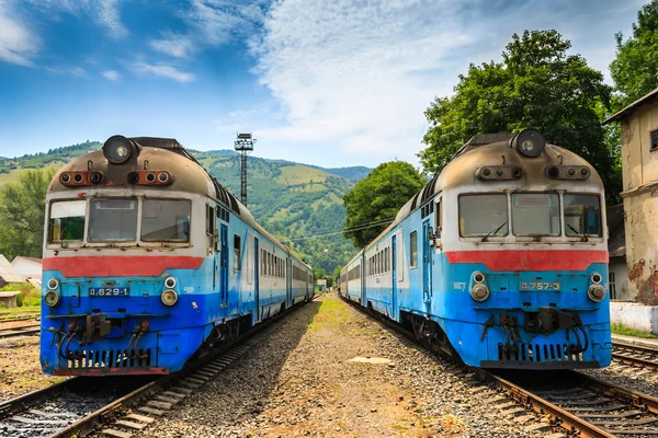 Mavi tren stand yan yana Dağları — Stok fotoğraf