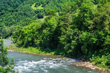 Nehri yakınındaki dağ eteklerinde döner.