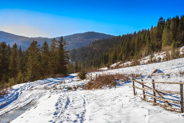 Holzzaun an der Straße Winterwald in den Bergen — Stockfoto