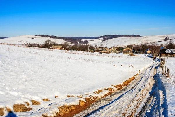 Дорога в старую деревню по снежному склону зимой — стоковое фото