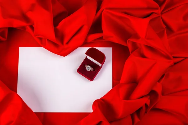 Tarjeta de amor con anillo de diamantes en una tela roja — Foto de Stock