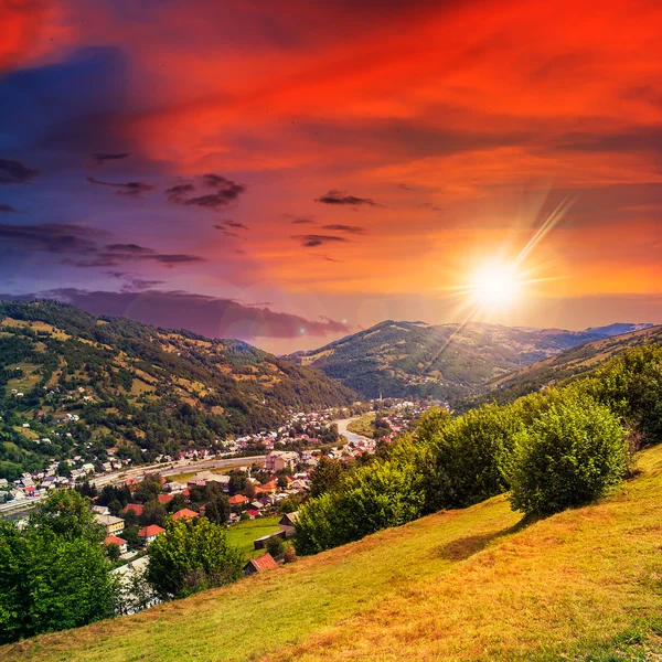 Dorp op heuvel weide met bos in berg bij zonsondergang — Stockfoto